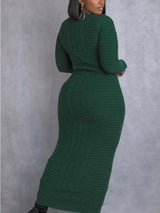Back view of a woman wearing a long green cable knit dress with long sleeves and a mock neck.