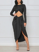 Woman wearing a black long-sleeve crop top with a twist-front detail and a matching high-slit ruched midi skirt.