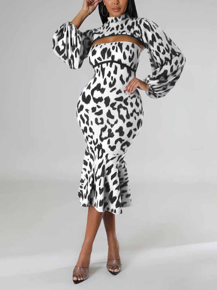 Woman wearing a black and white leopard print knit dress with a high neck, cut-out detail, long puff sleeves, and a mermaid hemline, posing with arms raised.