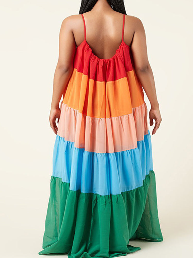 Back view of a woman in a flowing, tiered rainbow maxi dress.