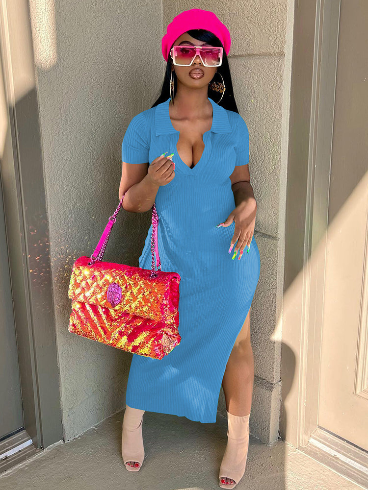 Woman wearing a blue ribbed knit midi dress with a V-neck collar and side slit, holding a colorful sequined handbag and a pink hat.