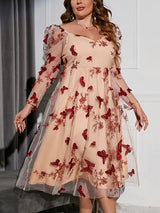 Plus-size woman wearing a sheer mesh A-line dress with red butterfly appliques and floral embroidery, featuring long puff sleeves and a sweetheart neckline.