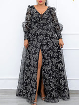 Woman wearing a long black and white floral print gown with a high slit, showcasing sheer puff sleeves and a V-neckline.