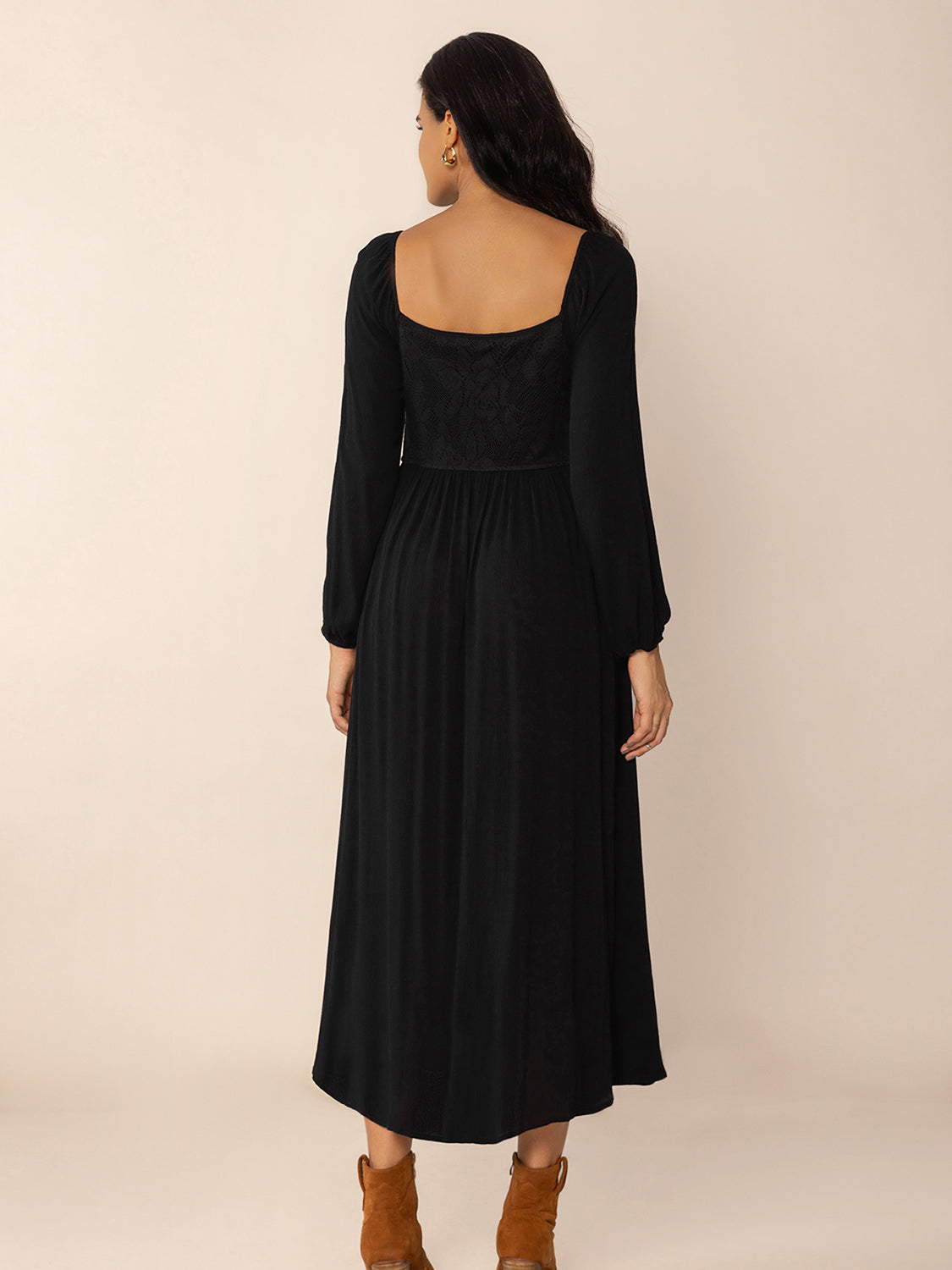 Back view of a woman wearing a black midi dress with a square neckline, long puff sleeves, and a corset-style waist detail.