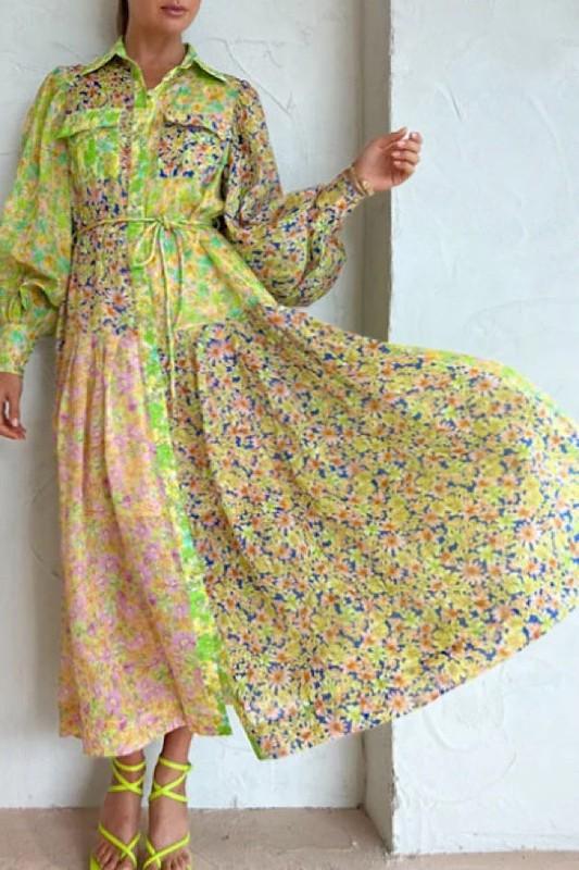 Woman wearing a long sleeve, collared, midi shirt dress with a tie waist and patchwork floral print in yellow, green, and pink.