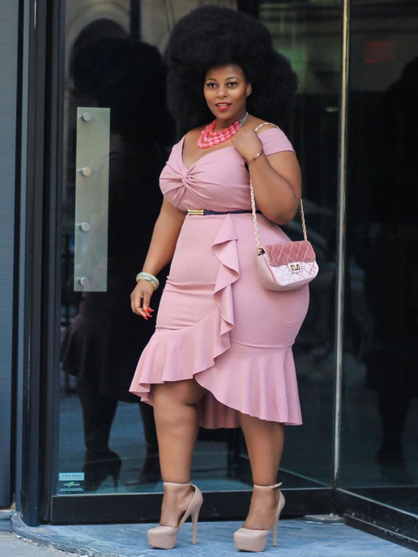 Side profile of a woman wearing a pink ruched dress with a ruffled hem and platform heels.