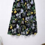 Close-up of the tiered hem and eyelet detailing on a black floral print midi dress
