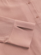 Close-up of the cuff and textured fabric of a pink collared shirt dress.