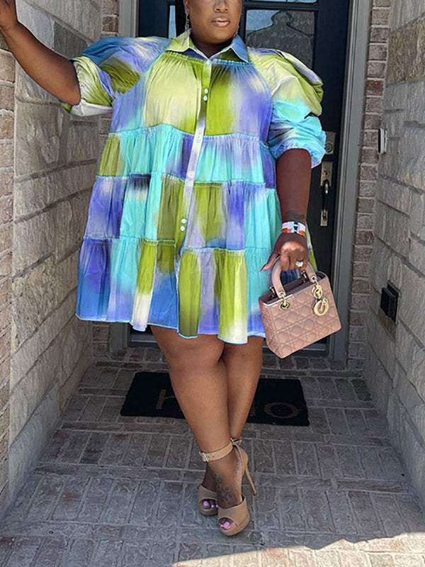 Model showcasing a short, tiered dress with a bold tie-dye pattern and voluminous sleeves