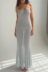 Woman wearing a sheer silver maxi dress in a studio setting.