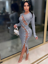 Woman wearing a grey ribbed knit midi dress with long sleeves, lace-up detailing on the sides and front, and a side slit.