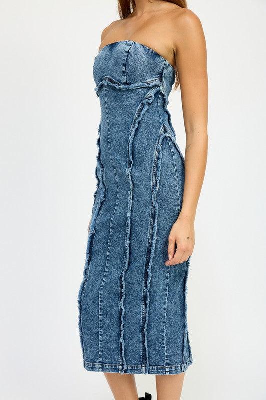 Close-up of the side of a blue strapless denim midi dress with paneled construction and raw edge detailing.