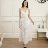 Woman wearing a white feather-trimmed midi dress with spaghetti straps and a v-neck, standing indoors.