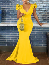 Woman wearing a yellow mermaid-style formal gown with ruffled cap sleeves and a deep V-neckline.