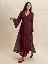 Full-body shot of a woman in a burgundy maxi dress with flared sleeves and intricate lace detailing on the skirt.