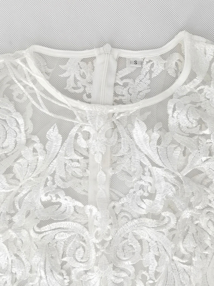 close-up of the neckline and upper chest area of a white lace dress, showing the intricate lace pattern and a zipper closure