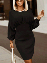 Woman wearing a black knit dress with gathered neckline and puffed sleeves