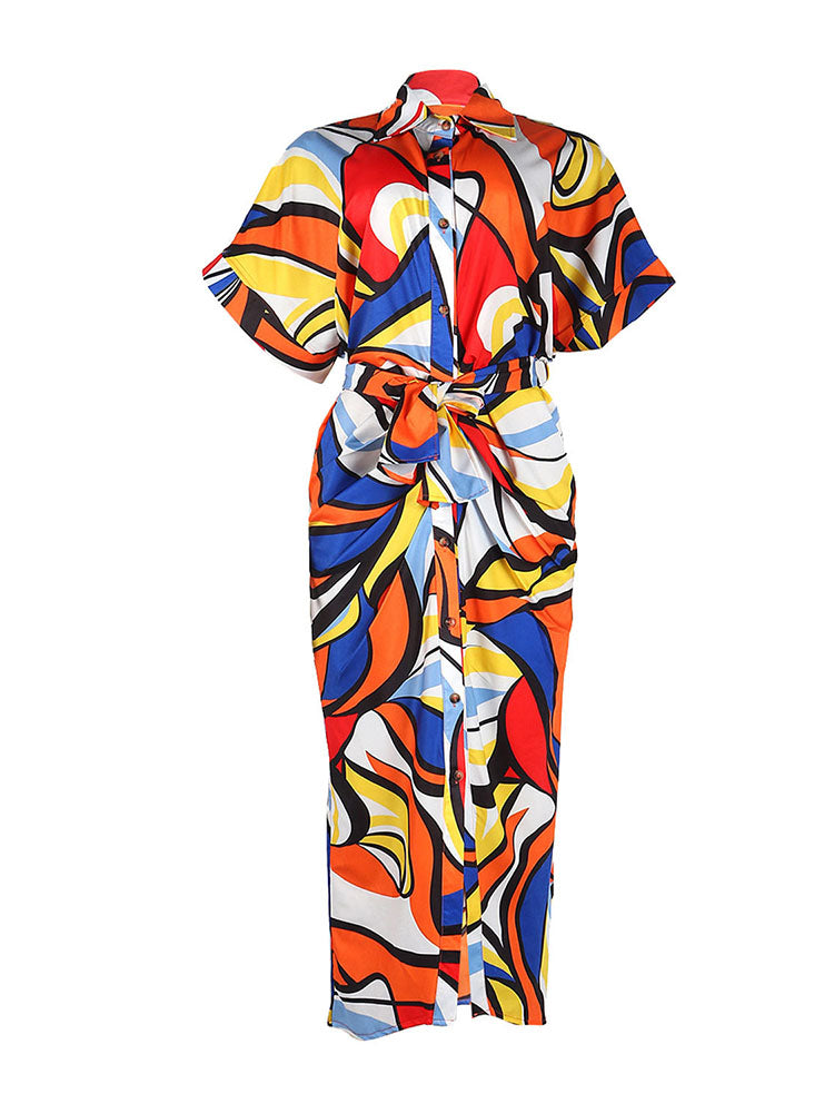 A colorful abstract print shirt dress with a tie waist and button front, laid flat.