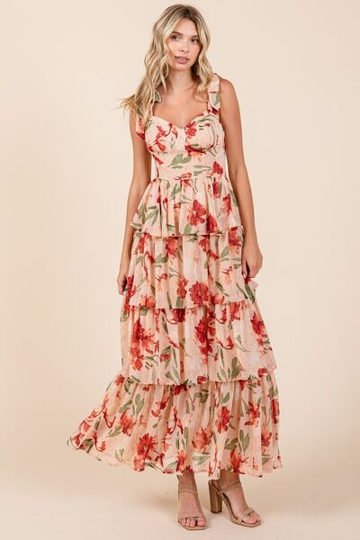 Full body shot of a woman twirling in a blush pink floral print tiered maxi dress