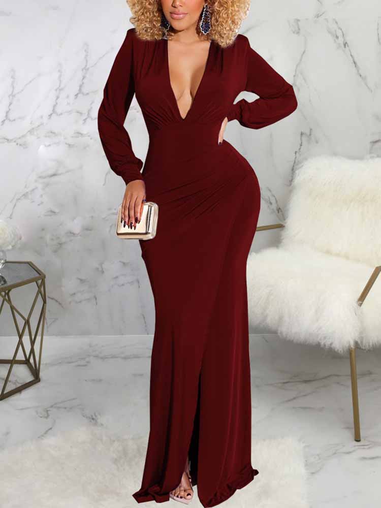 Woman wearing a long burgundy dress with a deep V-neckline, long sleeves, ruched detailing, and a high slit.