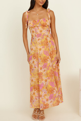 woman wearing a yellow midi dress with a pink and orange floral print, featuring tie shoulder straps and a square neckline