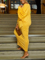 Side view of a woman in a yellow off-the-shoulder maxi dress with balloon sleeves, standing on stairs.