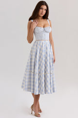 Woman wearing a blue and white gingham check midi dress with a sweetheart neckline and spaghetti straps.