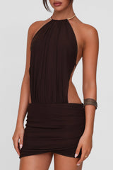 Close-up of a model wearing a brown ruched halter mini dress with side cutouts.