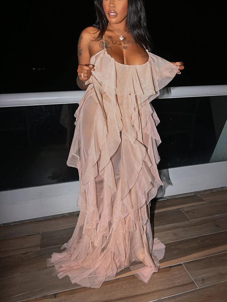Woman posing on a balcony in a sheer, floor-length ruffled gown.