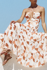 Close-up of the upper body of a woman in a halter maxi dress with a cut-out detail and geometric print.