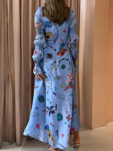 Back view of a woman in a light blue graphic print maxi dress with long sleeves and a keyhole back.
