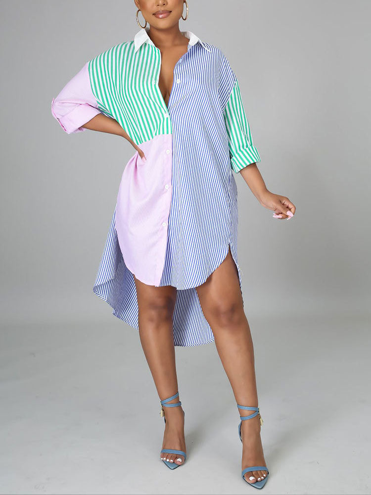 Woman wearing a colorblock striped button-down shirt dress with a high-low hem and blue heels.