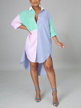 Woman wearing a colorblock striped button-down shirt dress with a high-low hem and blue heels.