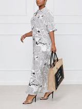 Woman walking to the side wearing a white and black newspaper print maxi dress and holding a canvas tote bag.