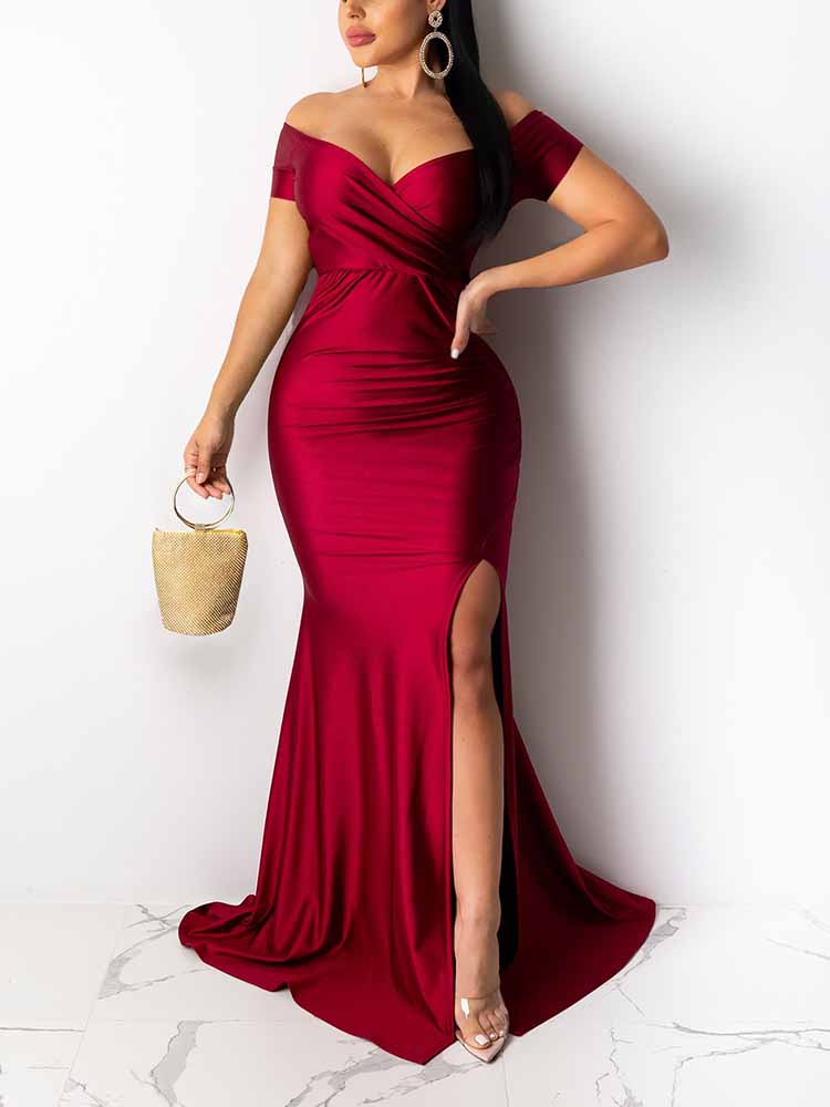 woman wearing a floor-length deep red satin gown with an off-the-shoulder neckline and a high slit
