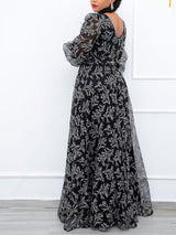 Rear view of a woman wearing a long black and white floral print gown with sheer puff sleeves and a V-neckline.