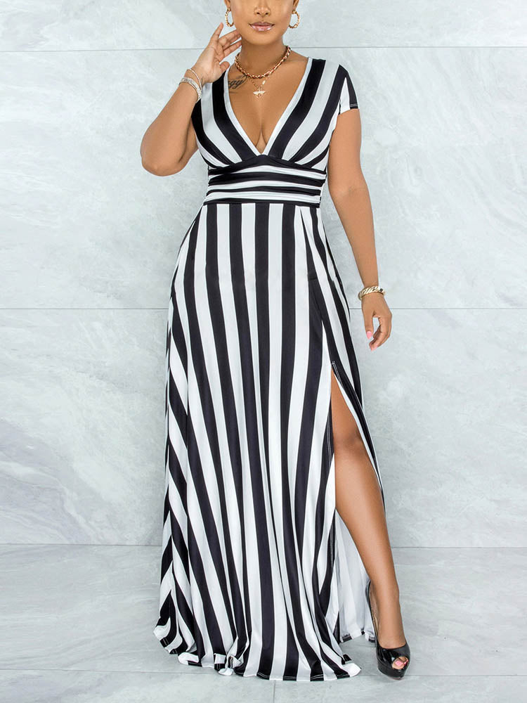 Close-up of a woman wearing a black and white striped maxi dress with a V-neck and high slit, touching her hair.