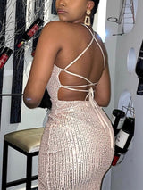 Back view of a woman in a champagne sequined dress with an open back and crisscross straps.