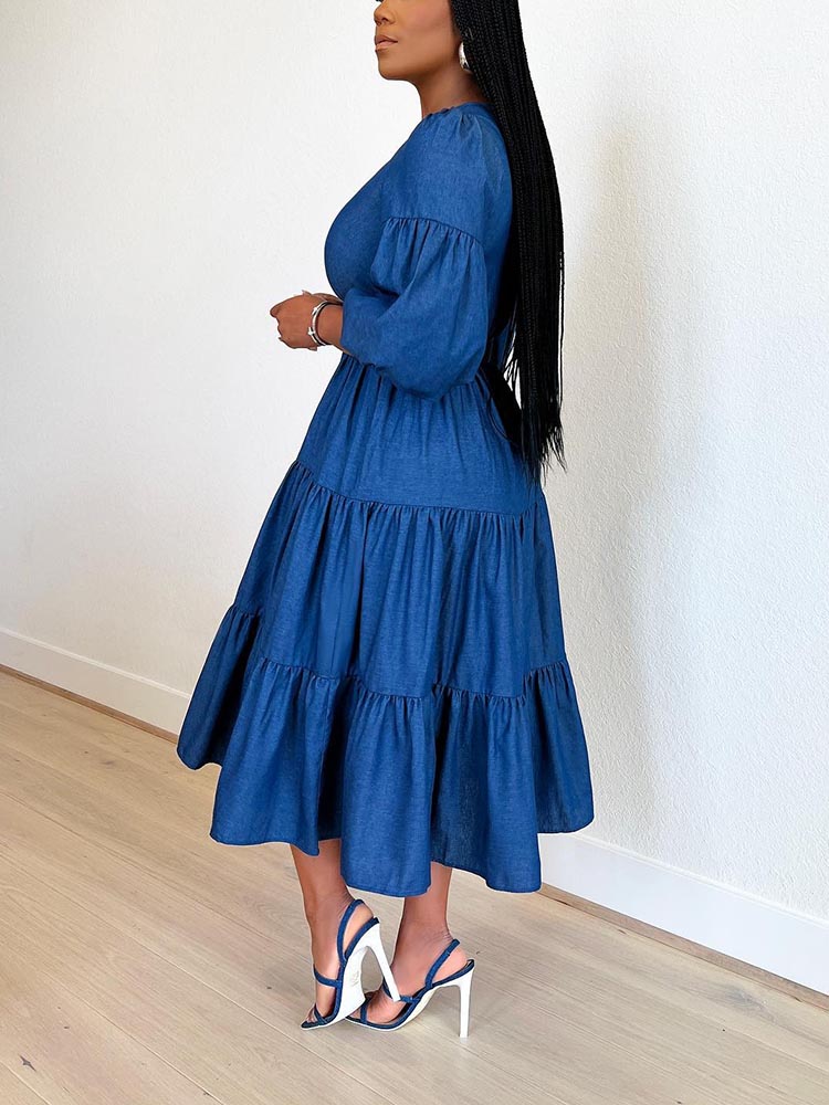 Side view of a woman in a blue denim midi dress with puff sleeves