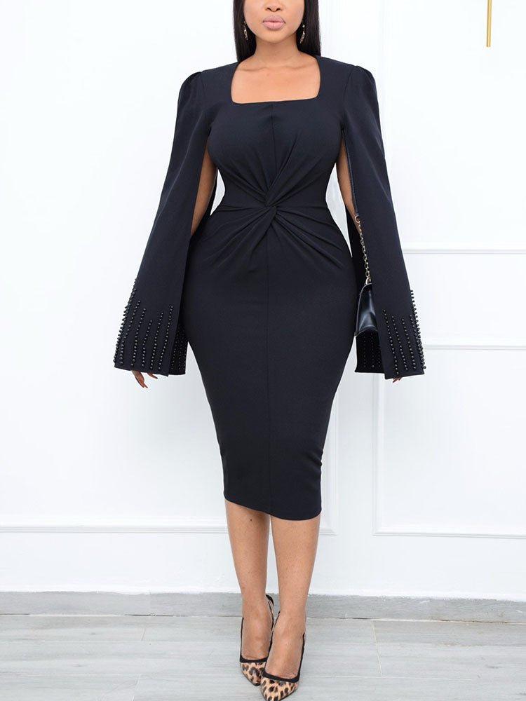 Woman wearing a black knee-length dress with cape sleeves and a square neckline.