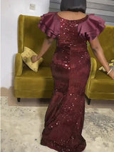 Back view of a woman in a burgundy sequined mermaid dress with ruffled sleeves.