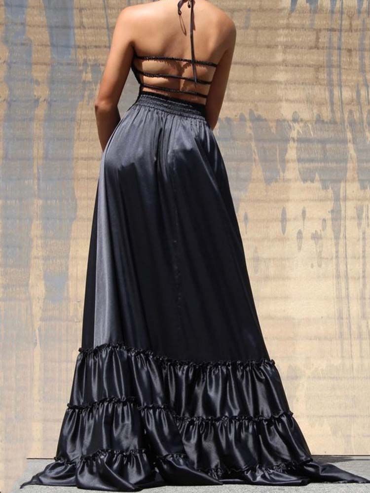 Back view of a woman in a black satin maxi dress with a strappy halter neckline and ruffled hem.