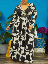 Woman wearing a black and white cow print maxi dress with long sleeves and a surplice neckline.