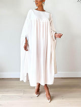 Woman wearing a white maxi dress with flowy sleeves and clear pointed-toe heels