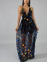 Woman wearing a black sequined maxi dress with a deep V-neck and halter straps.