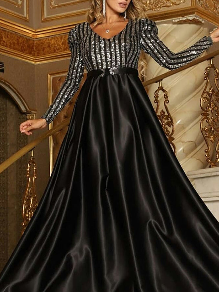 Woman wearing a black long-sleeved A-line formal dress with a sequined striped bodice and a satin skirt.