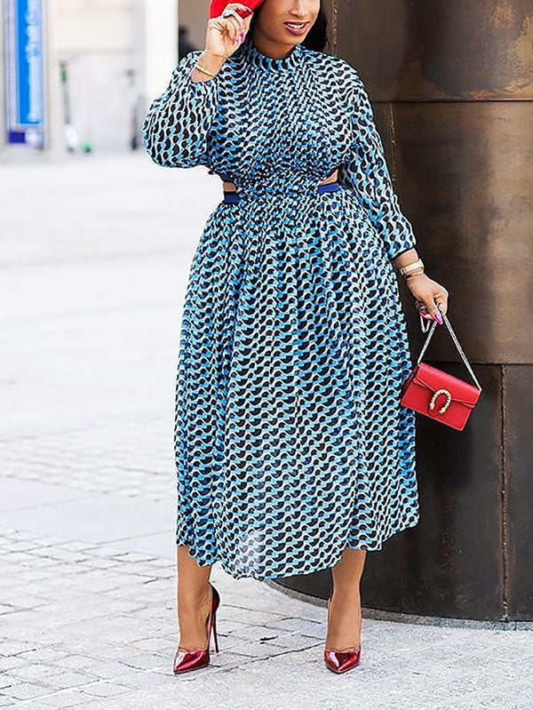 Woman wearing a blue and black geometric print midi dress with cut-out details and long sleeves, paired with red heels and a red handbag.