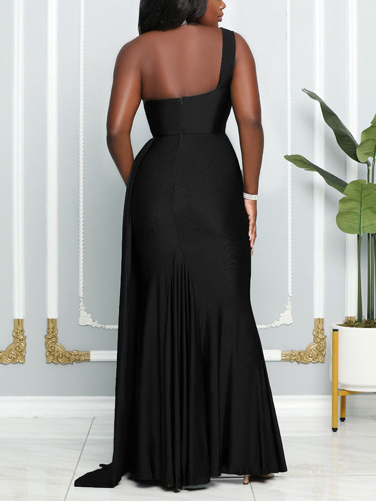 Back view of a woman wearing a floor-length, one-shoulder black dress with a high leg slit and pleated detail.