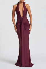 Woman wearing a burgundy floor-length halter dress with a deep V-neckline and ruched detailing.