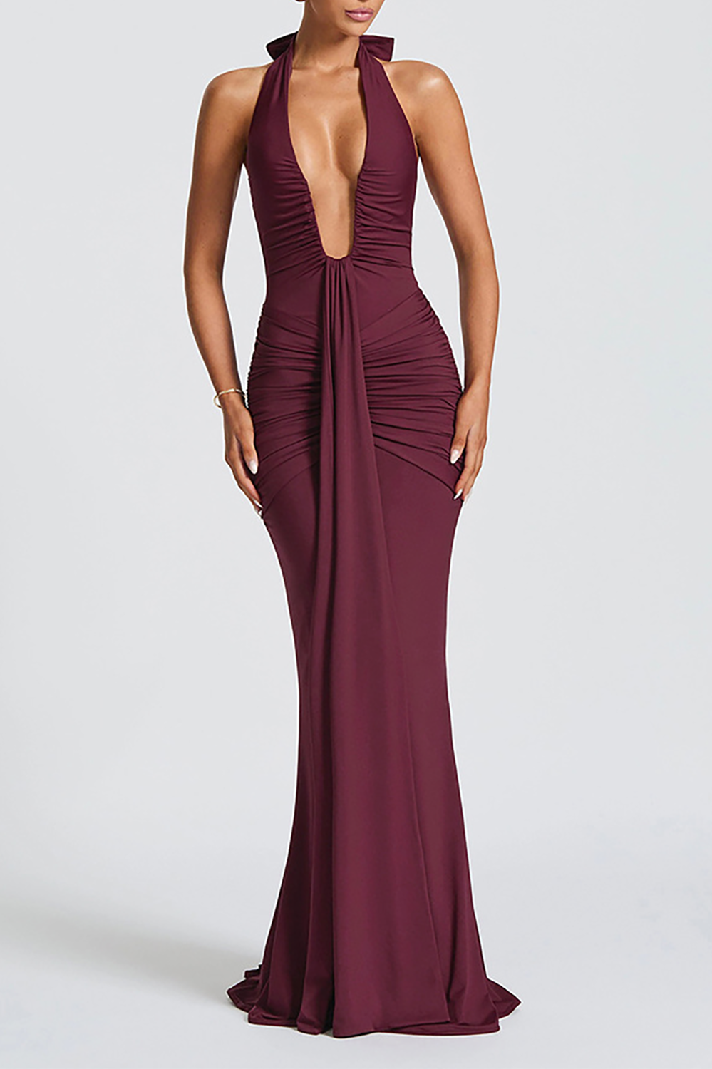 Woman wearing a burgundy floor-length halter dress with a deep V-neckline and ruched detailing.